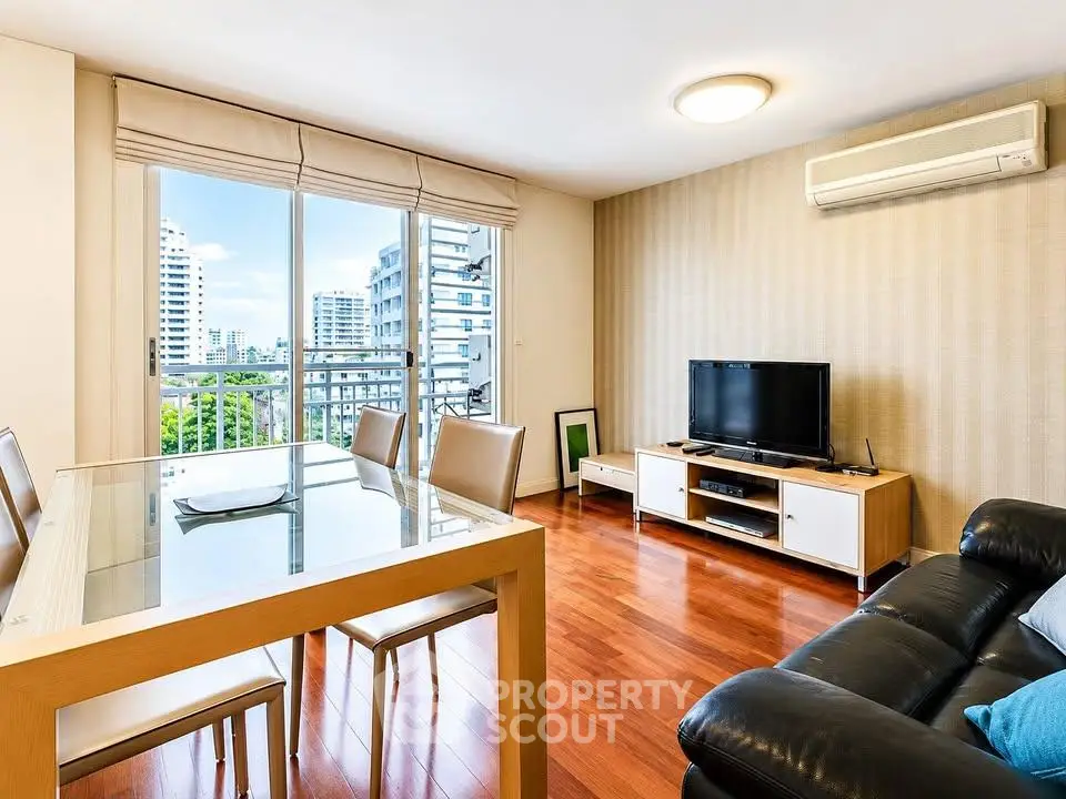 Modern living room with sleek furniture and city view, featuring hardwood floors and air conditioning.