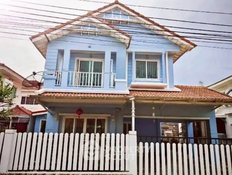 Charming blue two-story house with white picket fence and red roof, perfect for family living.