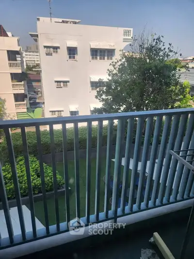 Charming balcony view overlooking lush garden in urban residential area.