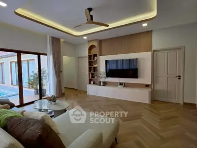 Luxurious living room with modern design, featuring elegant ceiling fan, cozy sofa, and poolside view.