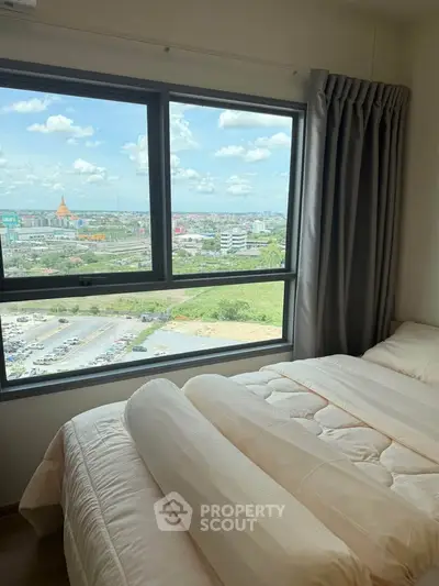 Cozy bedroom with a stunning city view through large windows, featuring a comfortable bed and elegant curtains.