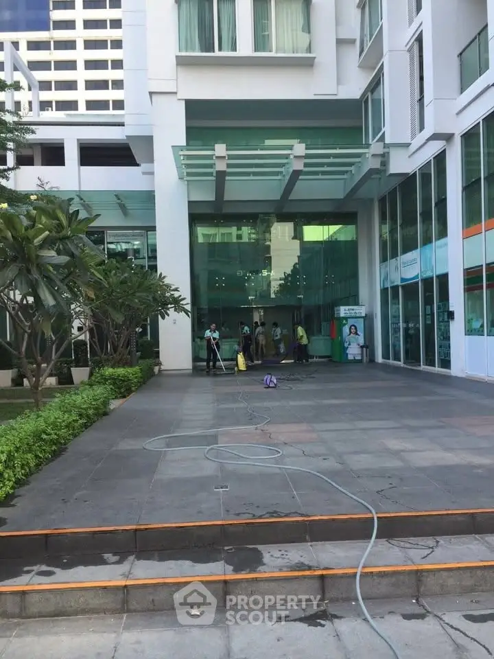 Modern building entrance with glass facade and landscaped greenery