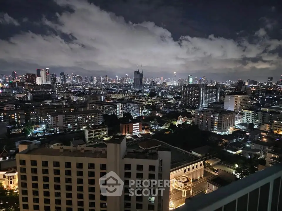 Stunning cityscape view from high-rise balcony at night, showcasing vibrant urban skyline.