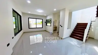 Spacious modern living room with glossy tiled floors and staircase, featuring large windows for natural light.