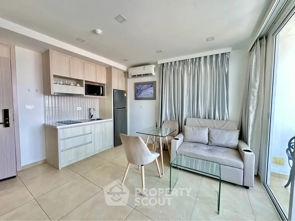 Modern open-plan living room with sleek kitchen and cozy seating area, featuring large windows for natural light.
