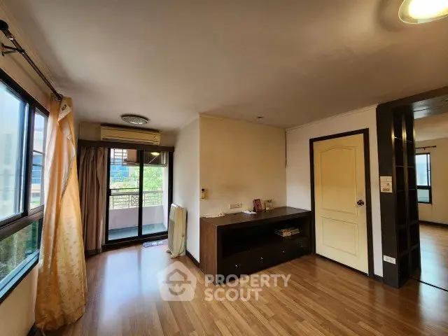 Spacious living room with wooden flooring and balcony access in modern apartment