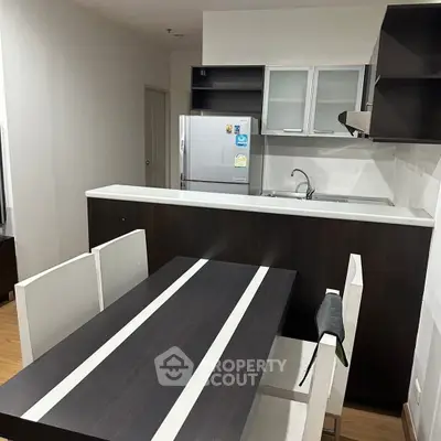 Modern kitchen with sleek cabinetry and dining area in contemporary apartment.