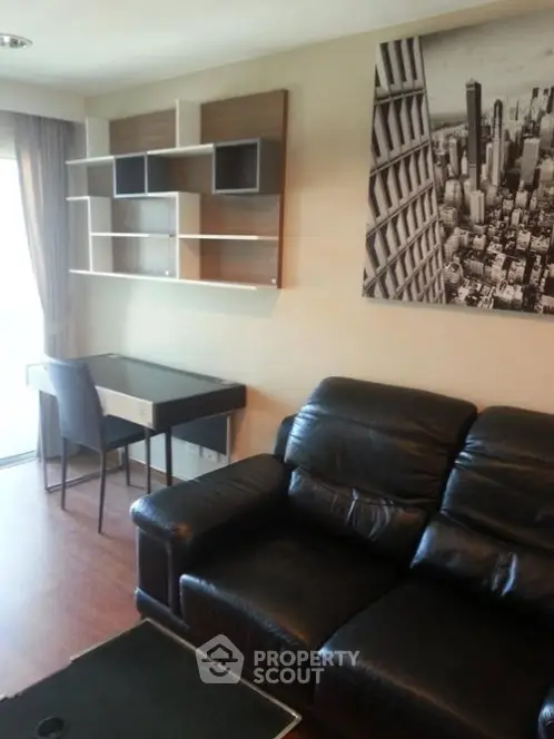 Modern living room with black leather sofa, wall art, and sleek shelving unit.