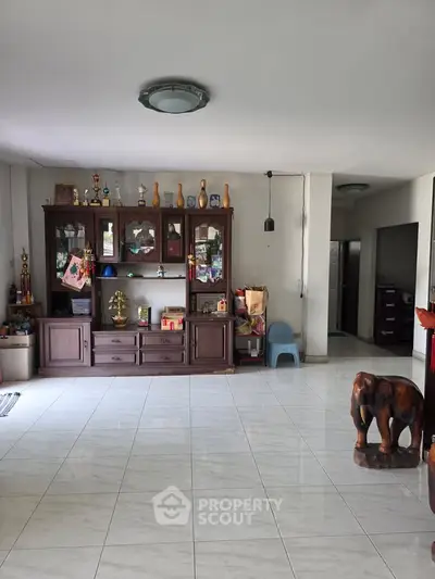 Spacious living room with elegant wooden cabinet and decorative elephant statue.