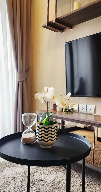 Modern living room with stylish decor, featuring a sleek TV setup and elegant orchid centerpiece.