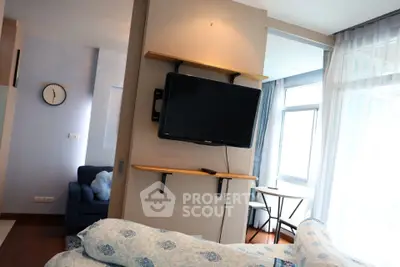 Modern living room with wall-mounted TV and cozy seating area in a bright apartment.