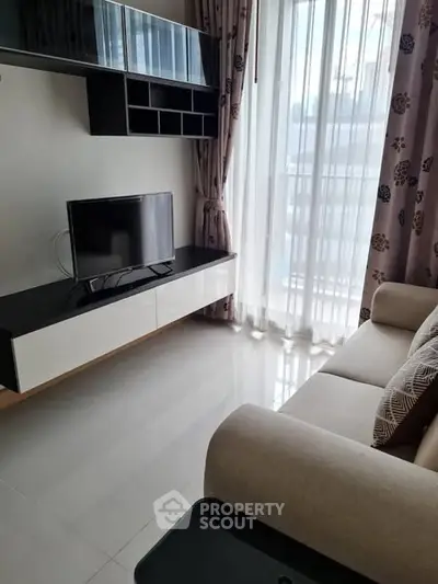 Modern living room with sleek TV setup and large window for natural light.
