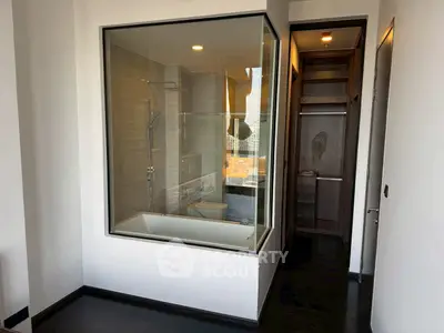 Modern apartment with unique glass-enclosed bathtub and sleek design.