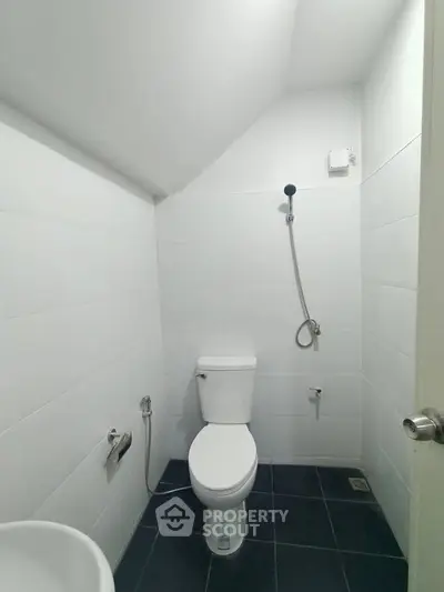 Modern minimalist bathroom with sleek white tiles and black flooring.