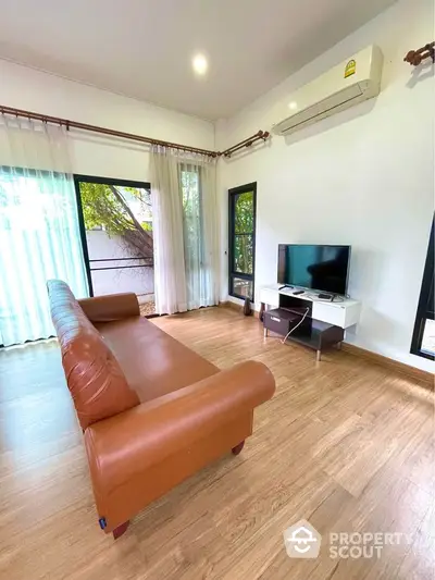 Spacious living room with leather sofa and modern TV setup