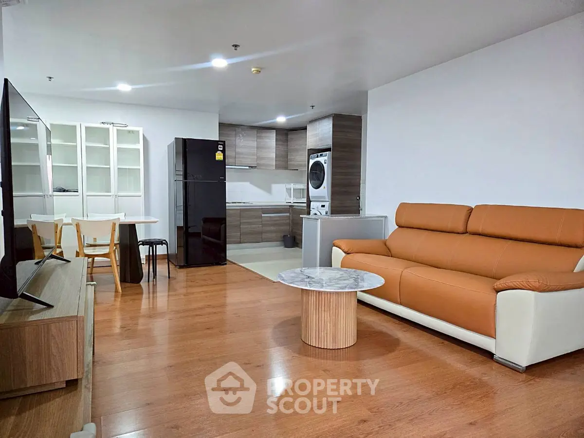 Modern open-plan living room with kitchen, featuring sleek appliances and stylish furniture.