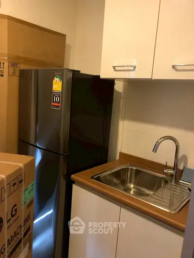 Compact kitchen with stainless steel sink and modern fridge