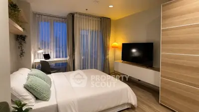 Modern bedroom with stylish decor, large TV, and cozy workspace, perfect for urban living.
