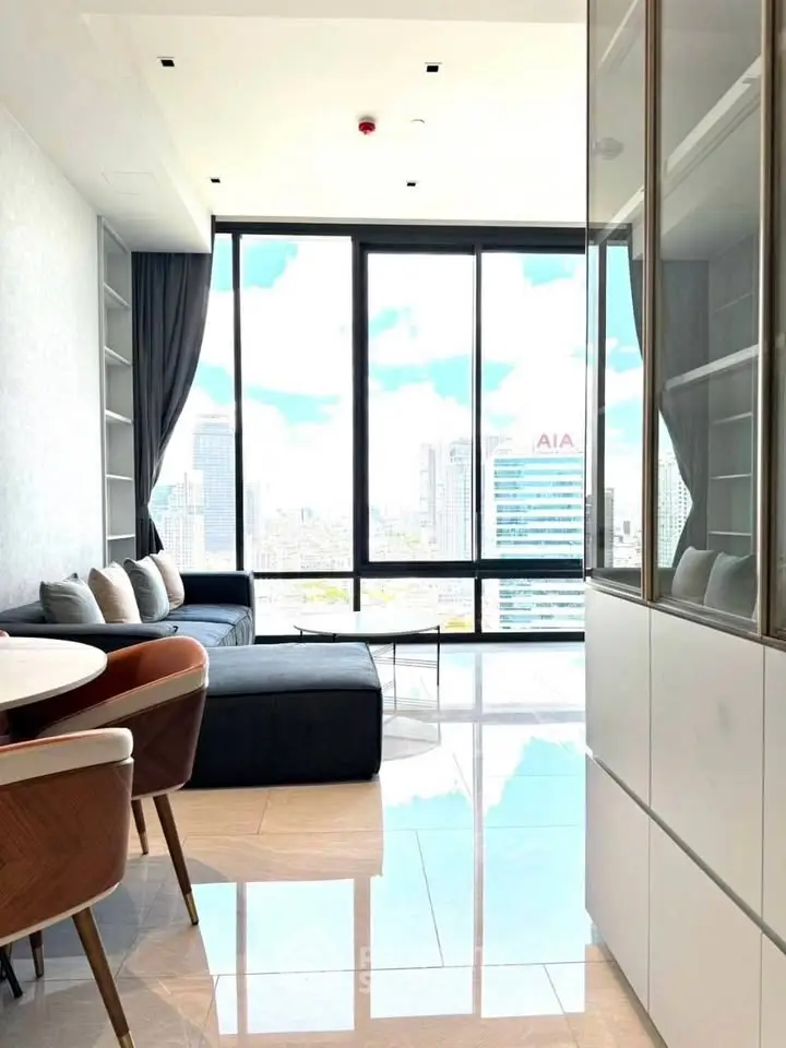 Modern living room with floor-to-ceiling windows offering stunning city views and elegant furnishings.