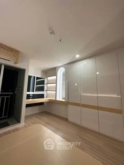 Modern interior with sleek cabinetry and built-in desk, featuring a stylish arched window for natural light.