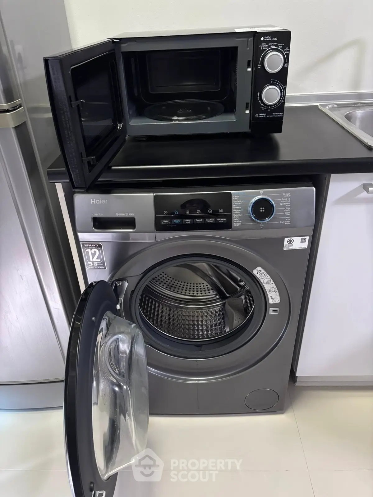 Modern kitchen with washing machine and microwave, sleek appliances for efficient living.