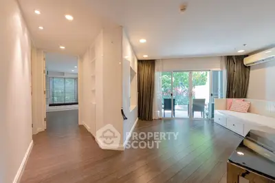 Spacious living room with modern decor and large windows opening to a lush garden view.