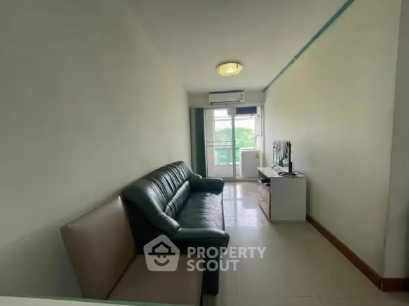 Cozy living room with leather sofa and TV, bright natural light from window.