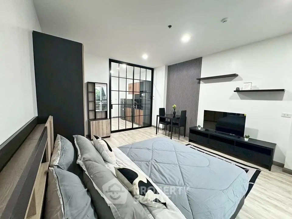 Modern bedroom with stylish decor and open layout, featuring a cozy bed and sleek furniture.