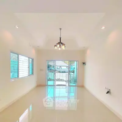 Spacious and bright living room with elegant chandelier and large windows offering natural light.