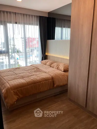 Modern bedroom with large windows and wooden flooring in a stylish apartment.