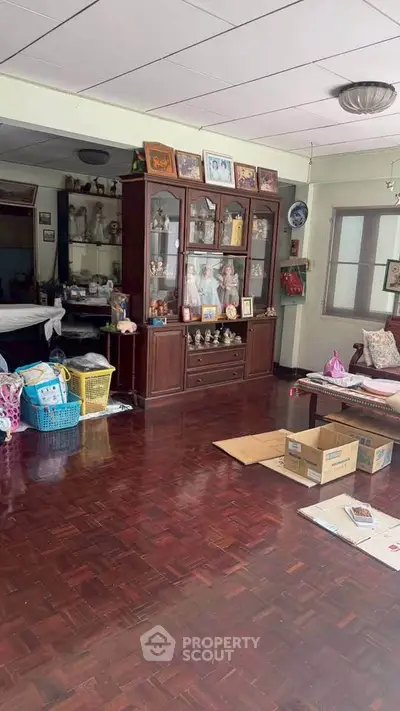 Spacious living room with wooden flooring and elegant display cabinet, perfect for family gatherings.