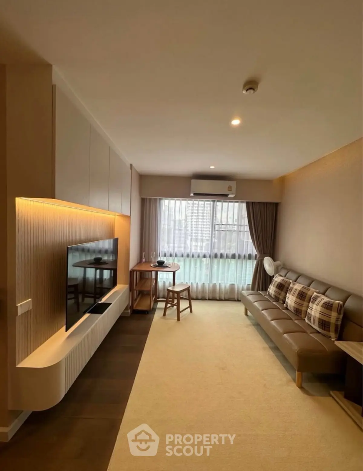 Modern living room with sleek TV unit and large window offering city view