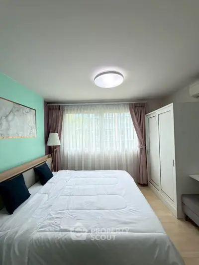 Spacious bedroom with large window and modern decor in a stylish apartment.