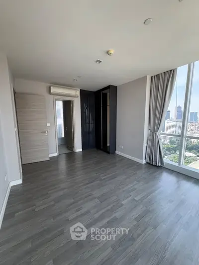Spacious modern apartment with large windows offering stunning city views, featuring sleek flooring and neutral decor.