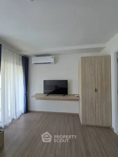 Modern living room with TV, air conditioning, and wooden flooring