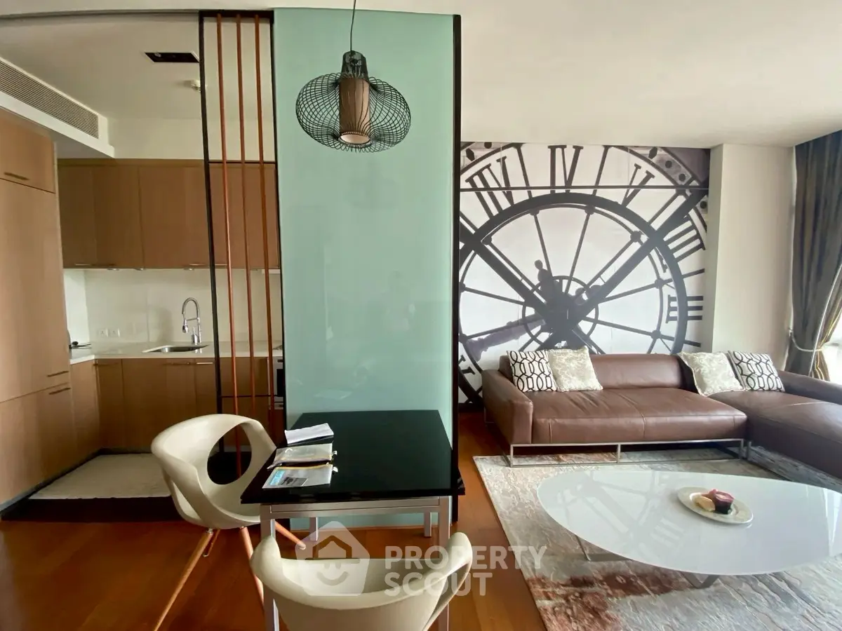 Modern living room with stylish decor and open kitchen layout, featuring a large clock mural and elegant furniture.
