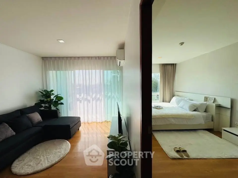 Modern open-layout living room and bedroom with natural light and stylish decor.