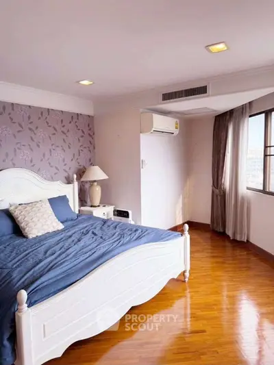 Spacious bedroom with elegant decor and large window offering natural light.