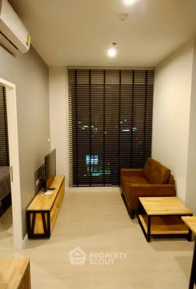 Modern living room with stylish furniture and large window blinds, perfect for cozy evenings.