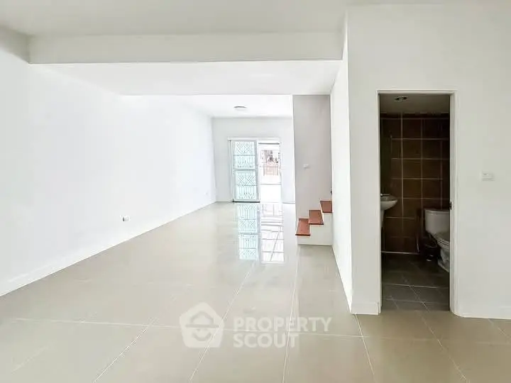 Spacious open-plan living area with tiled flooring and natural light.