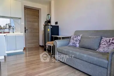 Modern living room with cozy sofa and compact kitchen in open layout apartment.