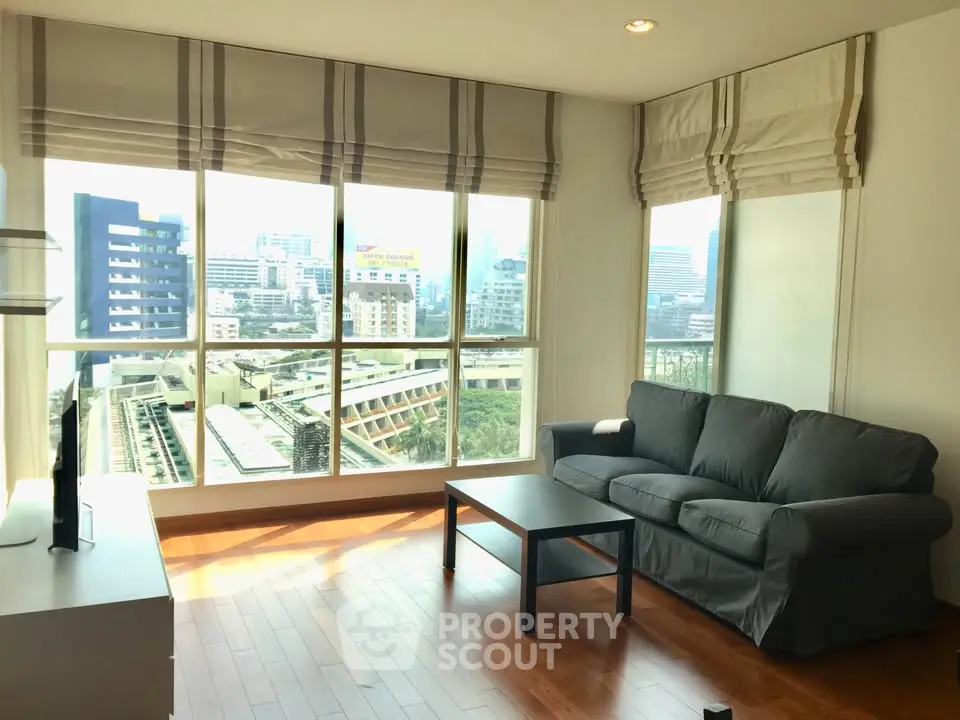 Spacious living room with large windows offering stunning city views and abundant natural light.