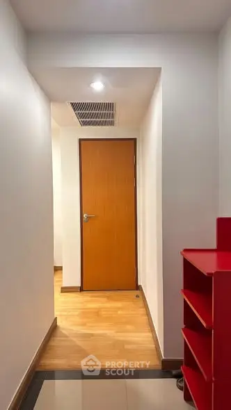 Modern hallway with wooden door and red shelving unit