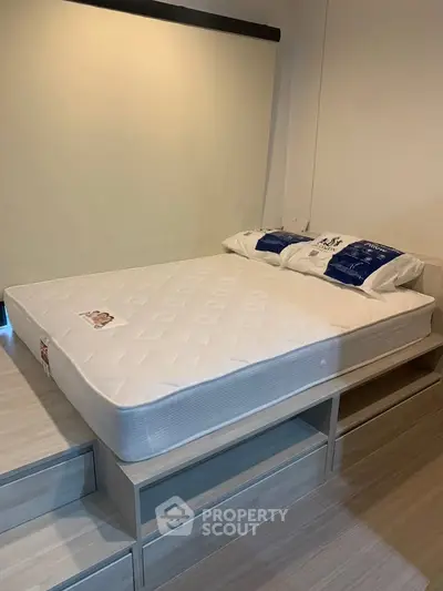 Modern bedroom with elevated bed and storage drawers in a stylish apartment.