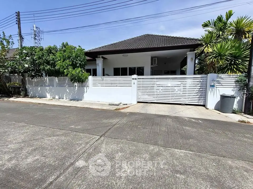 Charming single-story home with modern fence and lush greenery in a serene neighborhood.