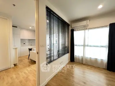 Modern apartment interior with open layout and wooden flooring, featuring a bright living area and kitchen.