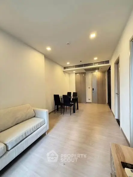 Modern living room with dining area, featuring sleek furniture and bright lighting in a stylish apartment.