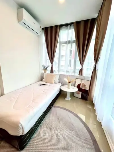 Cozy bedroom with large windows and modern decor in a high-rise apartment.