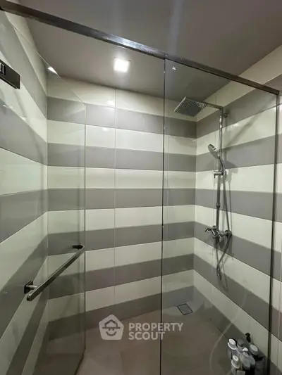 Modern bathroom with glass shower enclosure and striped tile design