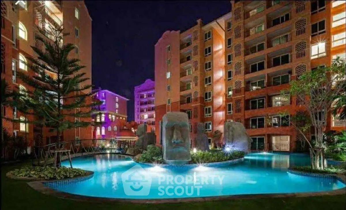 Luxurious apartment complex with illuminated pool and unique sculptures at night.